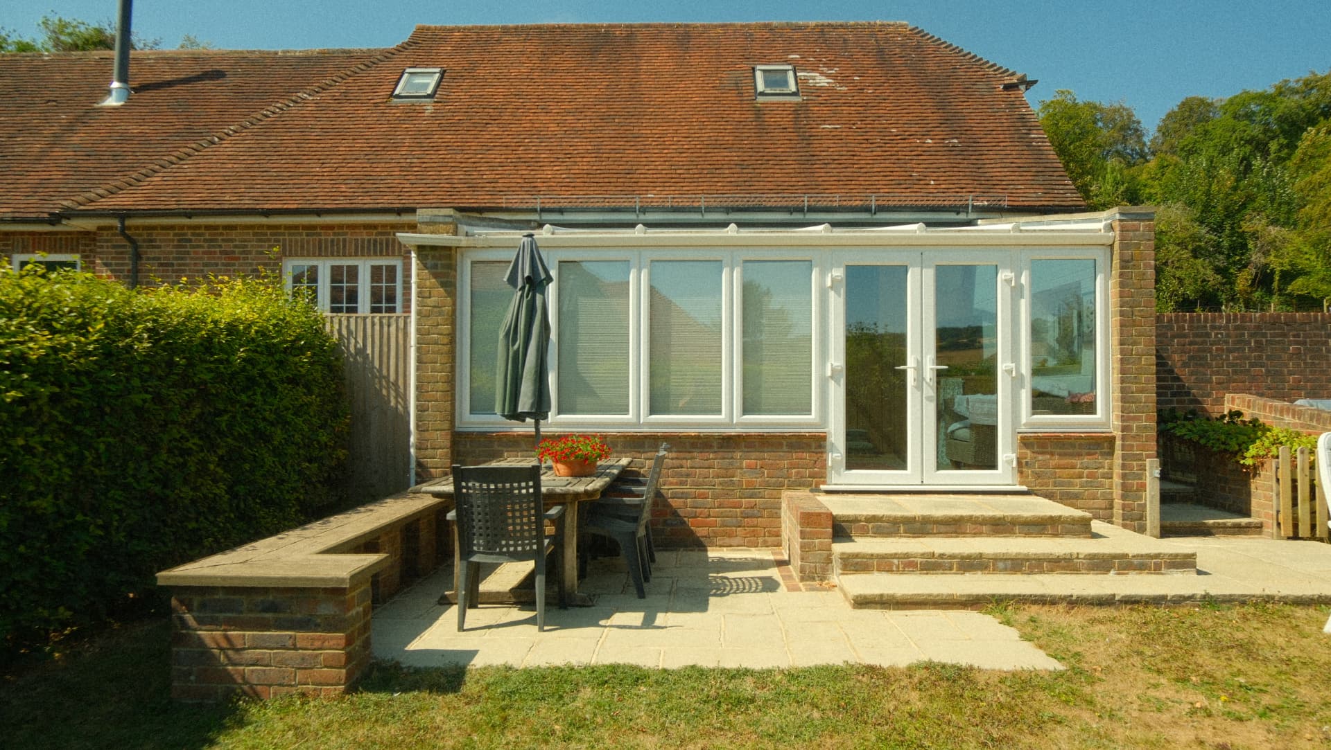 The sun terrace, with table, chairs and parasol outside the garden room