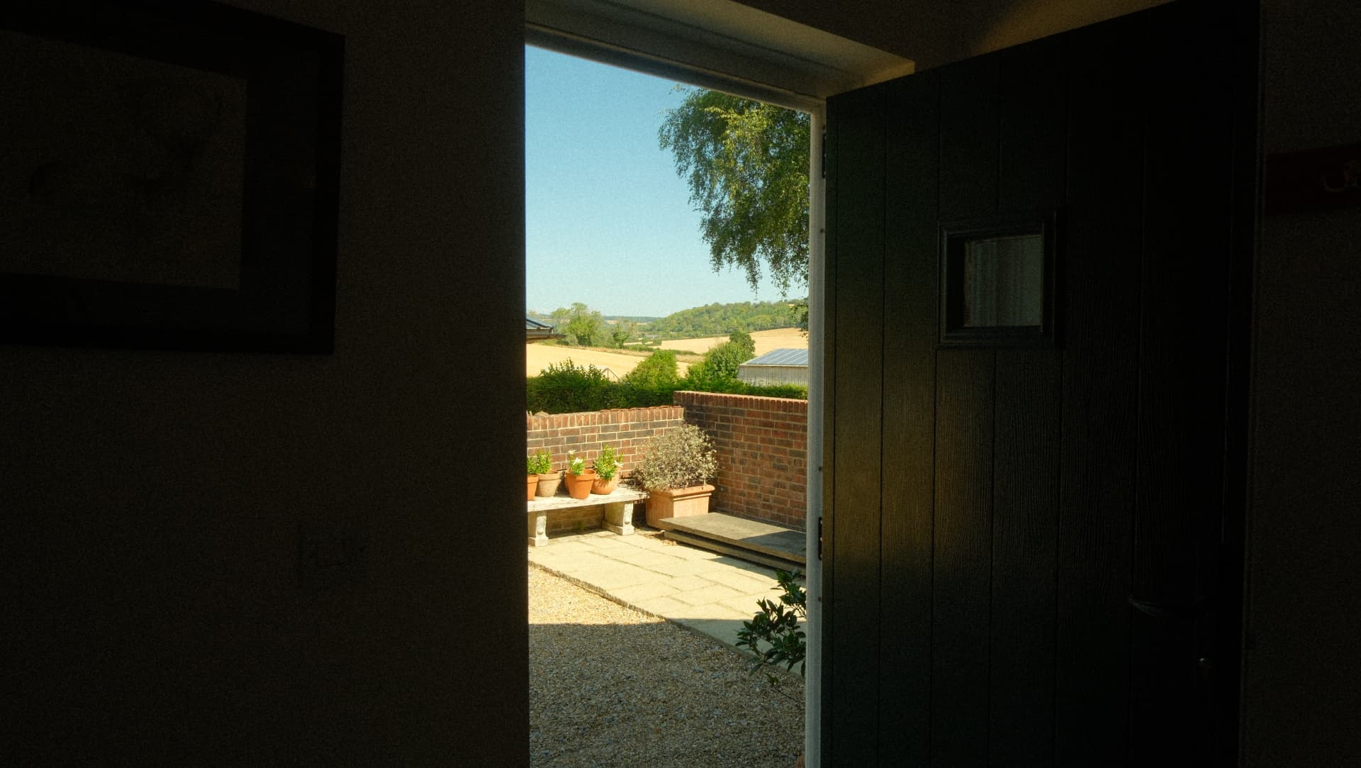 The front door opening onto the terrace and fields beyond
